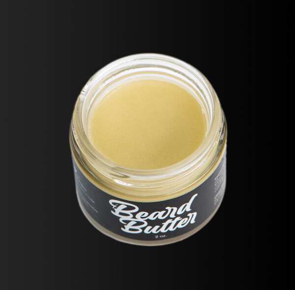 Open jar of Beard Butter beard car against black background.